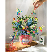 Load image into Gallery viewer, 3D floral arrangement with hummingbirds on a table with a cup of tea.