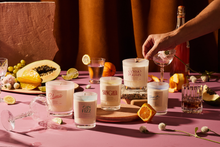 Load image into Gallery viewer, Table setting with various cocktails and a hand holding a glass.