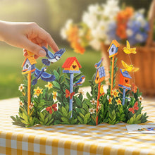 Load image into Gallery viewer, Colorful birdhouse and bird figurine set on a decorative table with flowers in the background.
